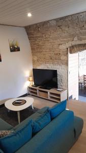 a living room with a blue couch and a tv at Maison rénové en pierre in Crotenay