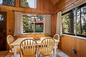 a dining room with a table and chairs and windows at Honey Bear Cabin in Carnelian Bay