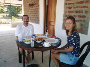 a man and a woman sitting at a table with food at Evara Homestay in Monaragala +2 photos