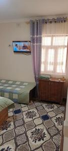 a bedroom with a bed and a window and a rug at Bro Hostel Angor in Termiz +3 photos