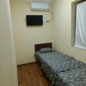 a small bedroom with a bed and a flat screen tv at Bro Hostel Angor in Termiz