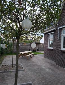 a picnic table and a tree in a yard at Wedderhoeske in Wedde