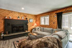 a living room with a couch and a fireplace at Riverfront Cabin w/ Hot Tub in Schroon Lake! in Schroon Lake
