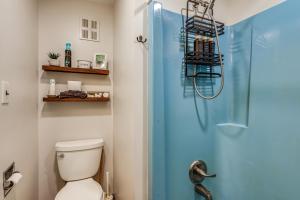 a bathroom with a toilet and a blue shower door at Riverfront Cabin w/ Hot Tub in Schroon Lake! in Schroon Lake +34 photos