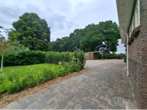 a brick driveway with green grass next to a house at Wedderhoeske in Wedde