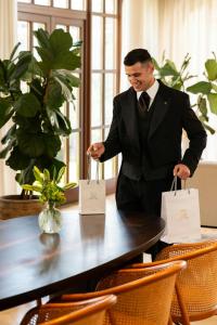 a man in a suit holding shopping bags at a table at The St. Regis Mardavall Mallorca Resort in Portals Nous +291 photos