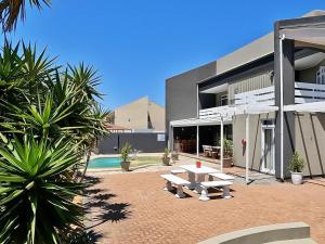 a building with a patio with a table and a pool at Beachwood Inn Melkbosstrand in Cape Town