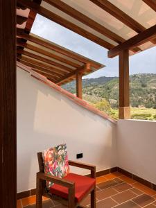 a balcony with a red chair and a large window at Hotel Cala in Cucaita