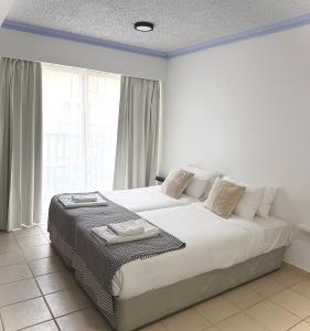 a bedroom with a large white bed with a window at Basilica Holiday Resort Apts in Paphos +33 photos
