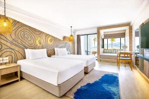 a hotel room with two beds and a table at LIV Hotel Phuket Patong Beachfront in Patong Beach +50 photos