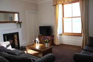 a living room with a couch and a table and a tv at Alexandra Apartment - stunning view in Oban