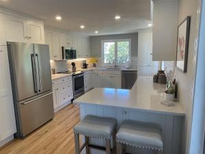 a kitchen with white cabinets and a stainless steel refrigerator at Great Hill in Kennebunk +30 photos