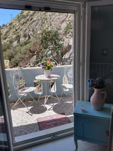 a glass door leading to a patio with a table and chairs at Colorful House Tsoutsouras in Tsoutsouros