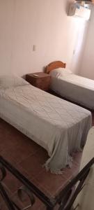 two beds in a room with a table and a bedskirts at El Legado in San Pedro