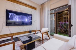 a living room with a couch and a tv on a wall at Luxury 98m2, City Boulevard View, Fountain View, Tashkent City in Tashkent