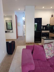 a living room with a purple couch and a kitchen at Villa Catalpas in Taroudant
