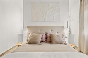 a white bedroom with a large bed with two pillows at Stillar Apartment near sea in Pula