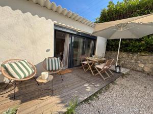 a wooden deck with a table and chairs and an umbrella at Mazets sous le pin in Le Rouret