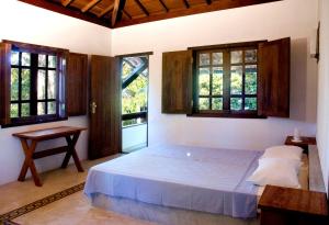 a bedroom with a large bed and two windows at Pousada Vila do Beco in Arraial d'Ajuda