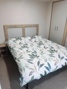 a bedroom with a bed with a white and green bedspread at St Nicolas in Girvan