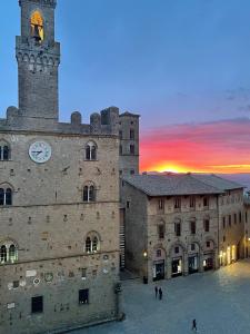 a large building with a clock tower with a sunset in the background at Garden Relax in Volterra
