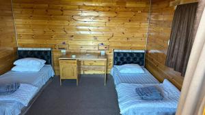 two beds and a desk in a room with wooden walls at Aydar Eco Yurt Camp in Ingichka