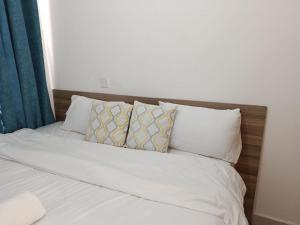 a bed with white sheets and pillows at HM Royal Homes in Nairobi +2 photos