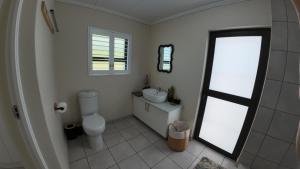a bathroom with a toilet and a sink and a window at Ebb & Flow Beach House in Oyster Bay +26 photos