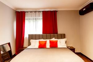 a bedroom with a large bed with red curtains at Aion Suites 301 in North Legon