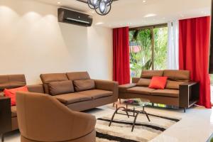 a living room with brown couches and red curtains at Aion Suites 301 in North Legon