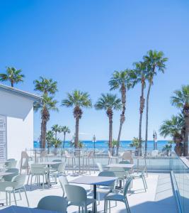 a patio with tables and chairs and palm trees at Epos by the Sea in Larnaca