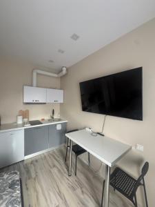 a kitchen with a table and a tv on the wall at Straume in Valmiera