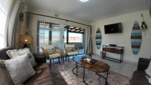 a living room with a couch and a table and surfboards at Ebb & Flow Beach House in Oyster Bay