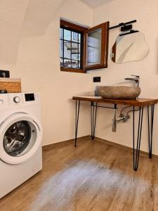a laundry room with a washing machine and a table at La Ca' nel Borgo in Tenno