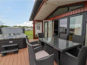a patio with a table and chairs and a grill at Honeysuckle lodge in Abergele
