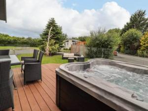 a hot tub on a wooden deck with a patio at Honeysuckle lodge in Abergele