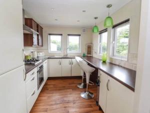a kitchen with white cabinets and a wooden floor at Honeysuckle lodge in Abergele