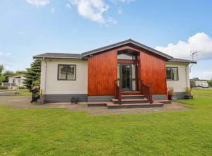 a small house with a wooden facade at Honeysuckle lodge in Abergele