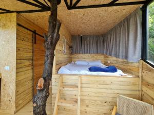 a bed in a wooden room with a tree in it at MONKEY MANSION - Luxury Treehouse - Private Escape with outdoor hot Tub in Abū Mīzān