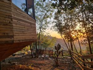 a wooden house with a fence and the sunset at MONKEY MANSION - Luxury Treehouse - Private Escape with outdoor hot Tub in Abū Mīzān