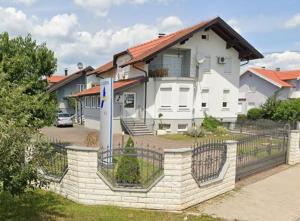 a large white house with a fence in front of it at Rooms Ikar in Velika Gorica