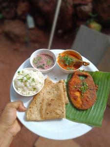 a plate of food with rice and bread and dips at Varsha farm house in Guhagar