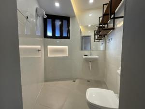 a white bathroom with a toilet and a sink at Studio moderno com ar condicionado central in Aracaju