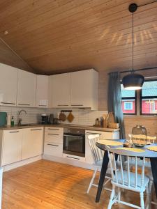 a kitchen with white cabinets and a table with chairs at Gjørven Hytter in Flåm