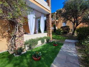 a garden with green grass and white curtains at Maison Dora in Villasimius