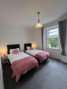 two beds in a room with a window at Ronebhal Guest House in Oban +29 photos