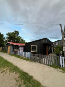 a black house with a fence next to a road at Central Apartment in Cochrane