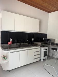 a kitchen with white cabinets and a sink and a stove at Casa da Glória 2 in Diamantina