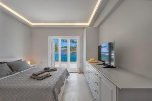 a bedroom with a bed and a flat screen tv at Sunset Villa in Posidhonía