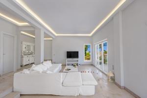 a living room with a white couch and a tv at Sunset Villa in Posidhonía +22 photos